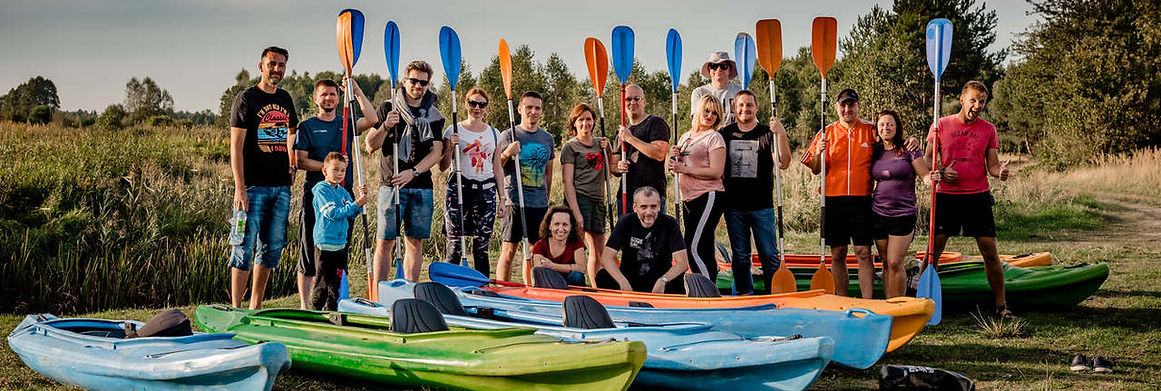 Grupa z kolorowymi kajakami nad Pilicą